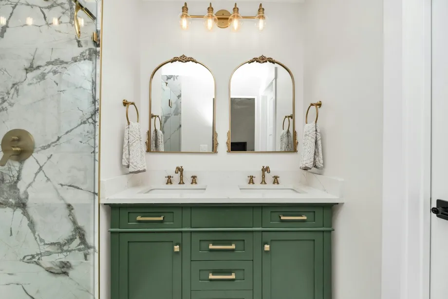 Bathroom with marble countertops and green vanity cabinets